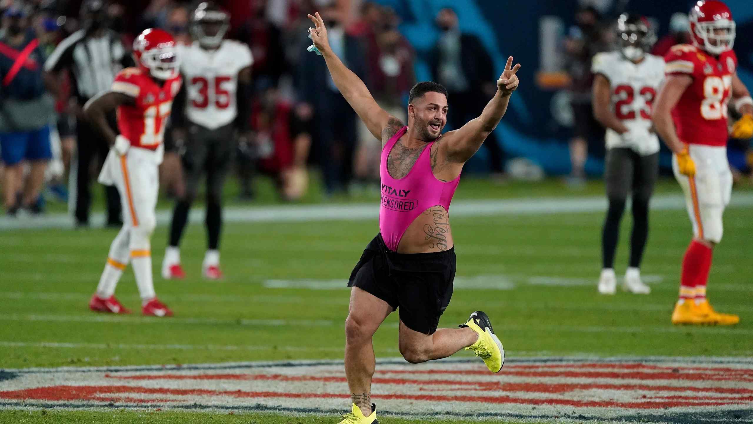A man interrupting a football game by running onto the field while wearing a loud outfit.